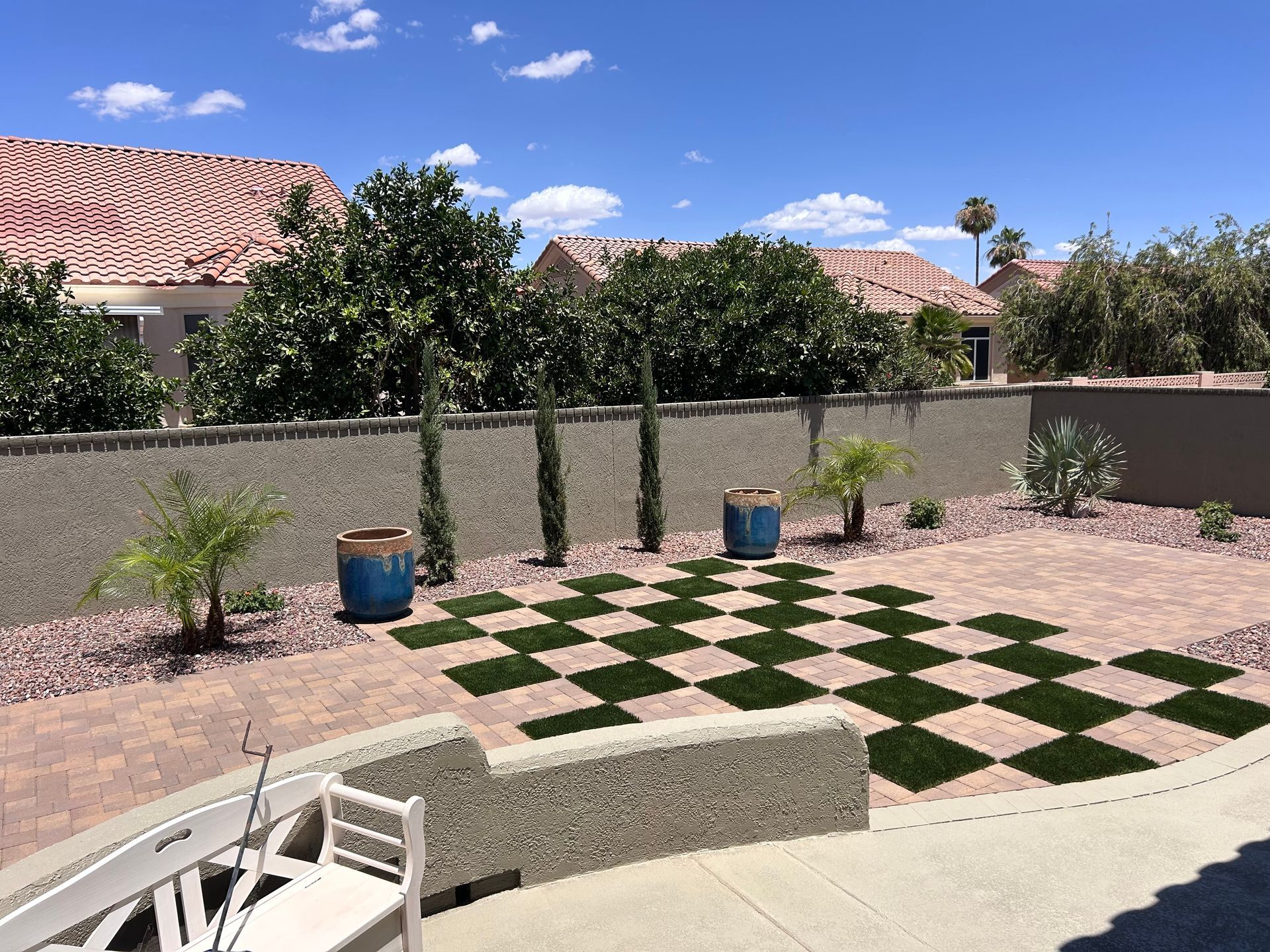 A patio with a lot of grass and a tree in the background.
