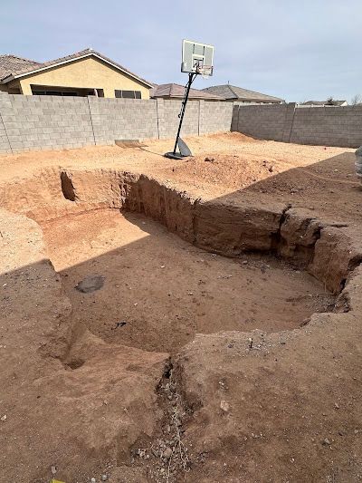 A basketball hoop is sitting in the middle of a dirt field.