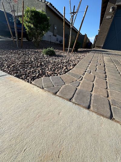 A brick walkway leading to a house with a blue garage door.
