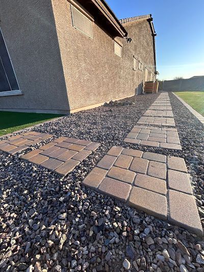 A walkway made of bricks and gravel in front of a house.