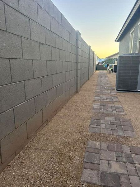 A brick wall and a brick walkway leading to a house.
