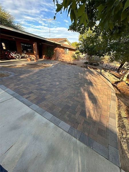 A brick driveway is being built in front of a house.