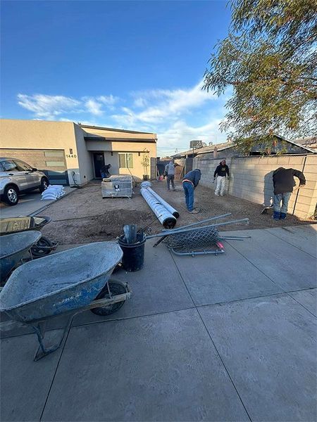A group of people are working on a driveway in front of a house.
