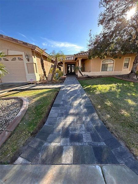There is a walkway leading to the front of the house.