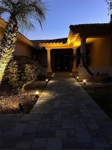 A brick walkway leading to a house at night