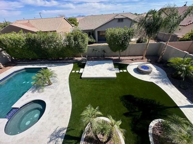 Backyard pool and spa with green lawn, white patio, and desert-style landscaping