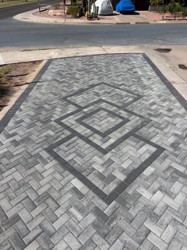 Gray geometric brick driveway with a diamond pattern leading to a street curb