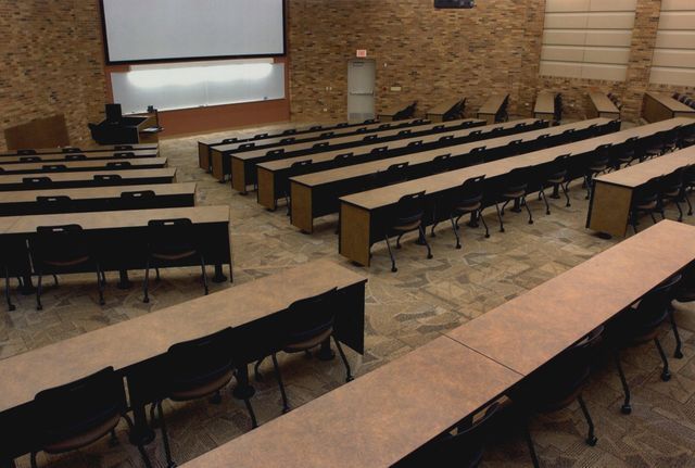 Rows of long tables and chairs in a lecture hall