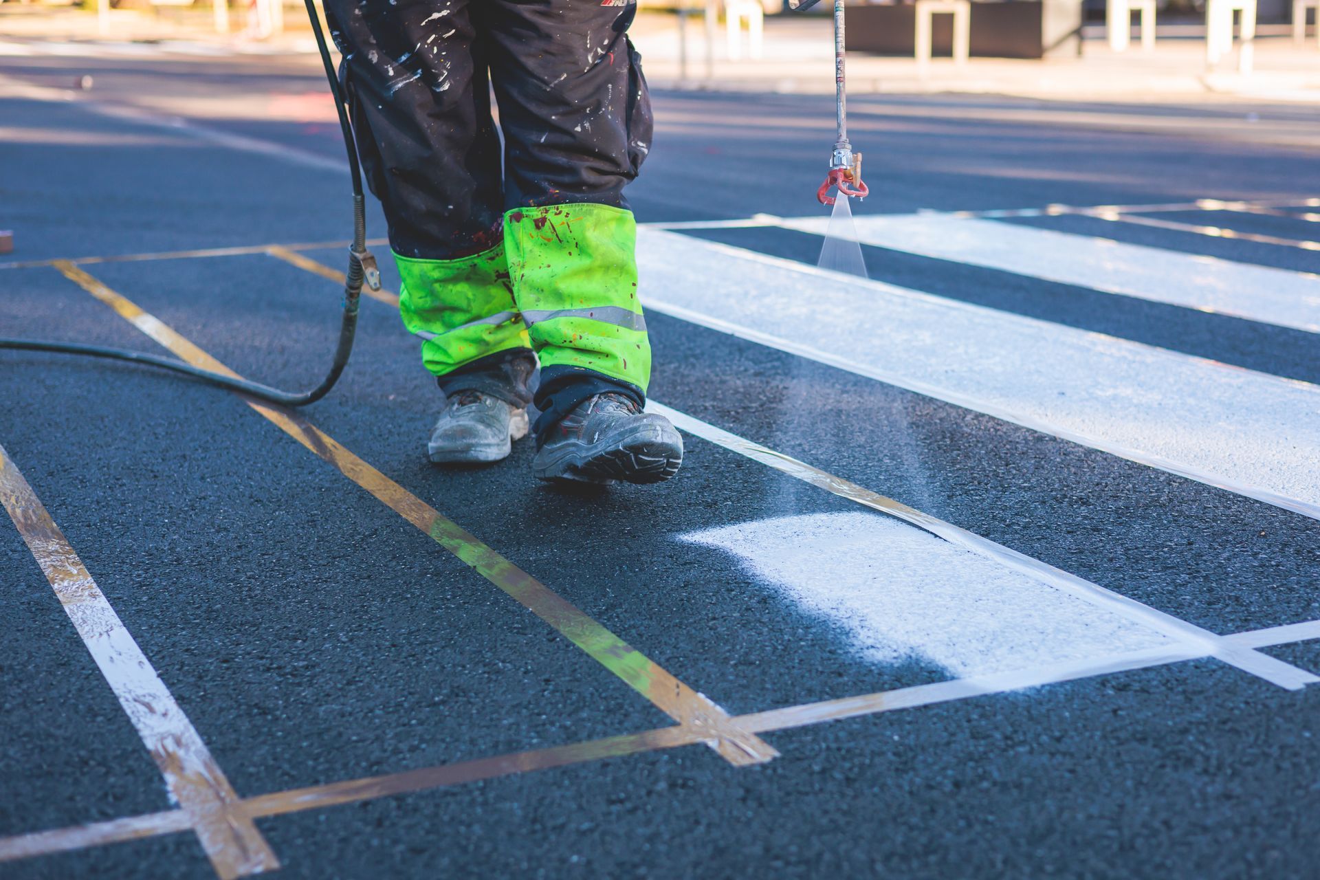 A person is spraying paint on a crosswalk.