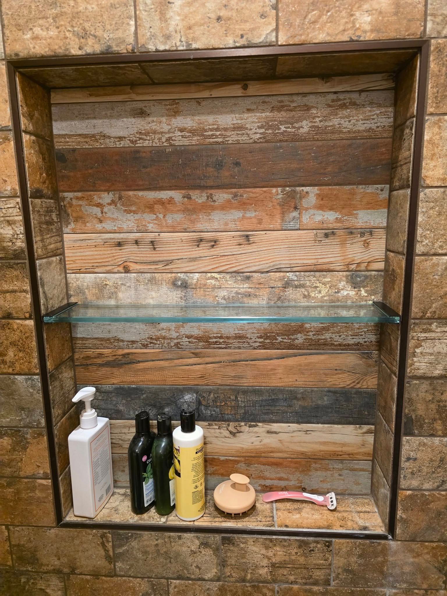 A shower niche with a glass shelf in a bathroom.