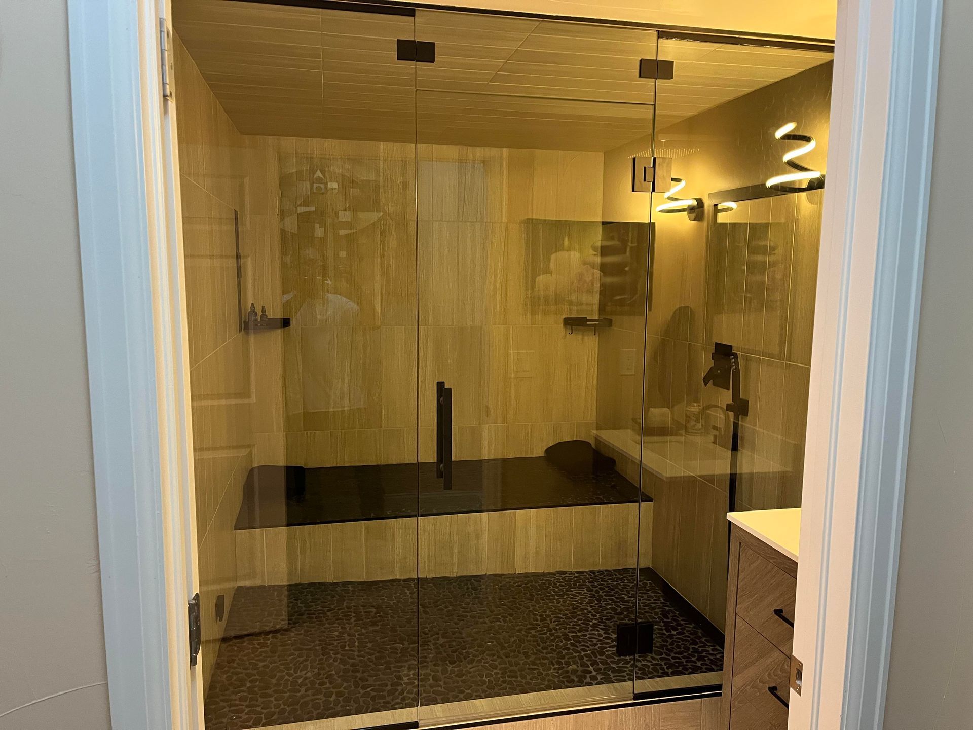 A bathroom with a walk in shower and a sink.