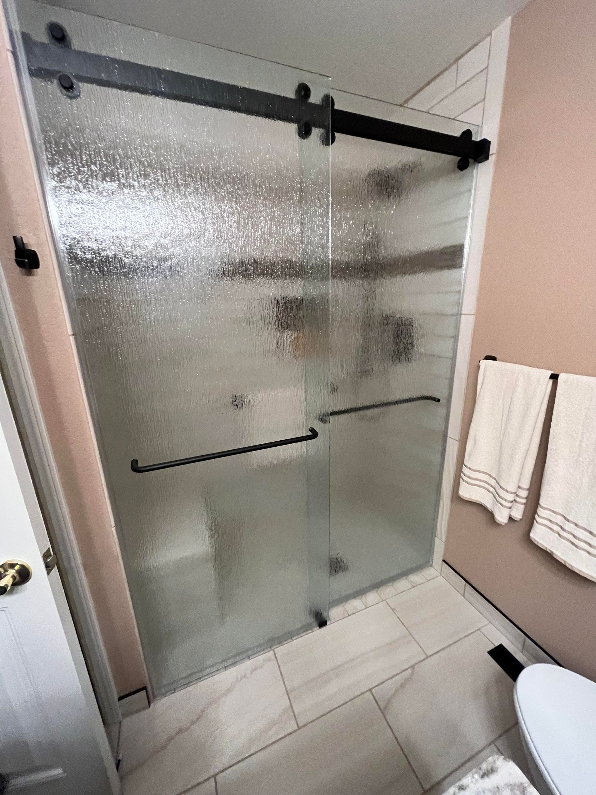 A bathroom with a sliding glass shower door and a toilet.