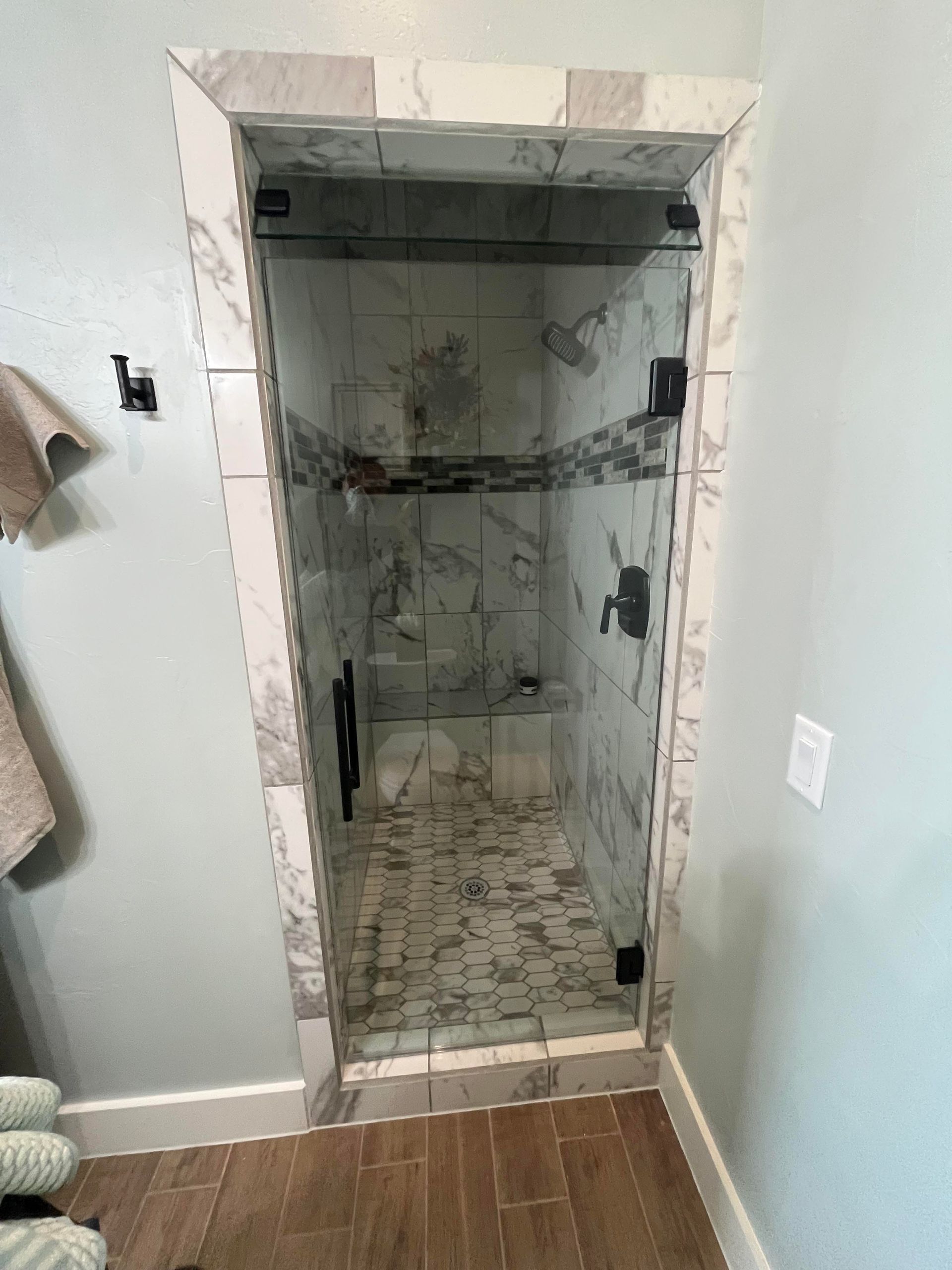 A bathroom with a walk in shower with a glass door.