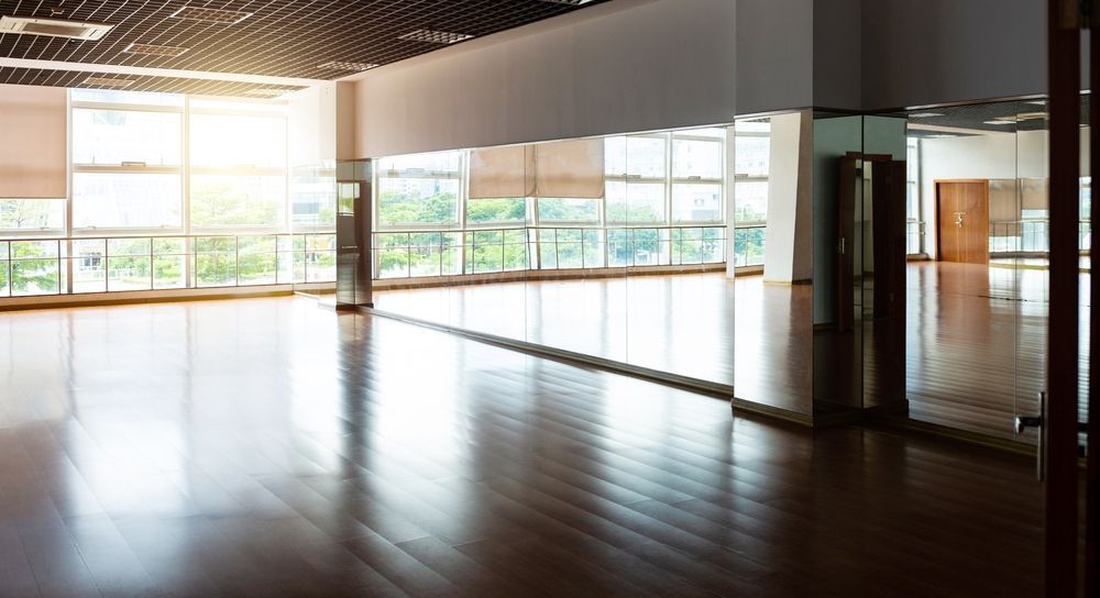 An empty dance studio with a lot of windows and mirrors.