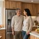 Pareja adulta feliz junto a una nevera moderna en su cocina.