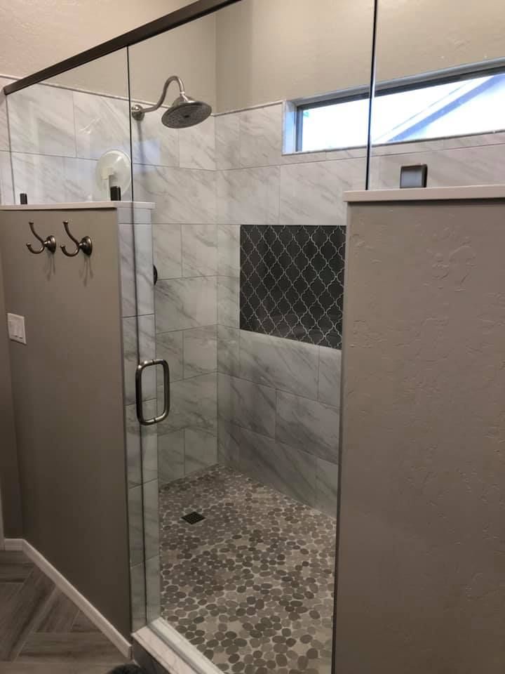 A bathroom with a walk in shower with a glass door.