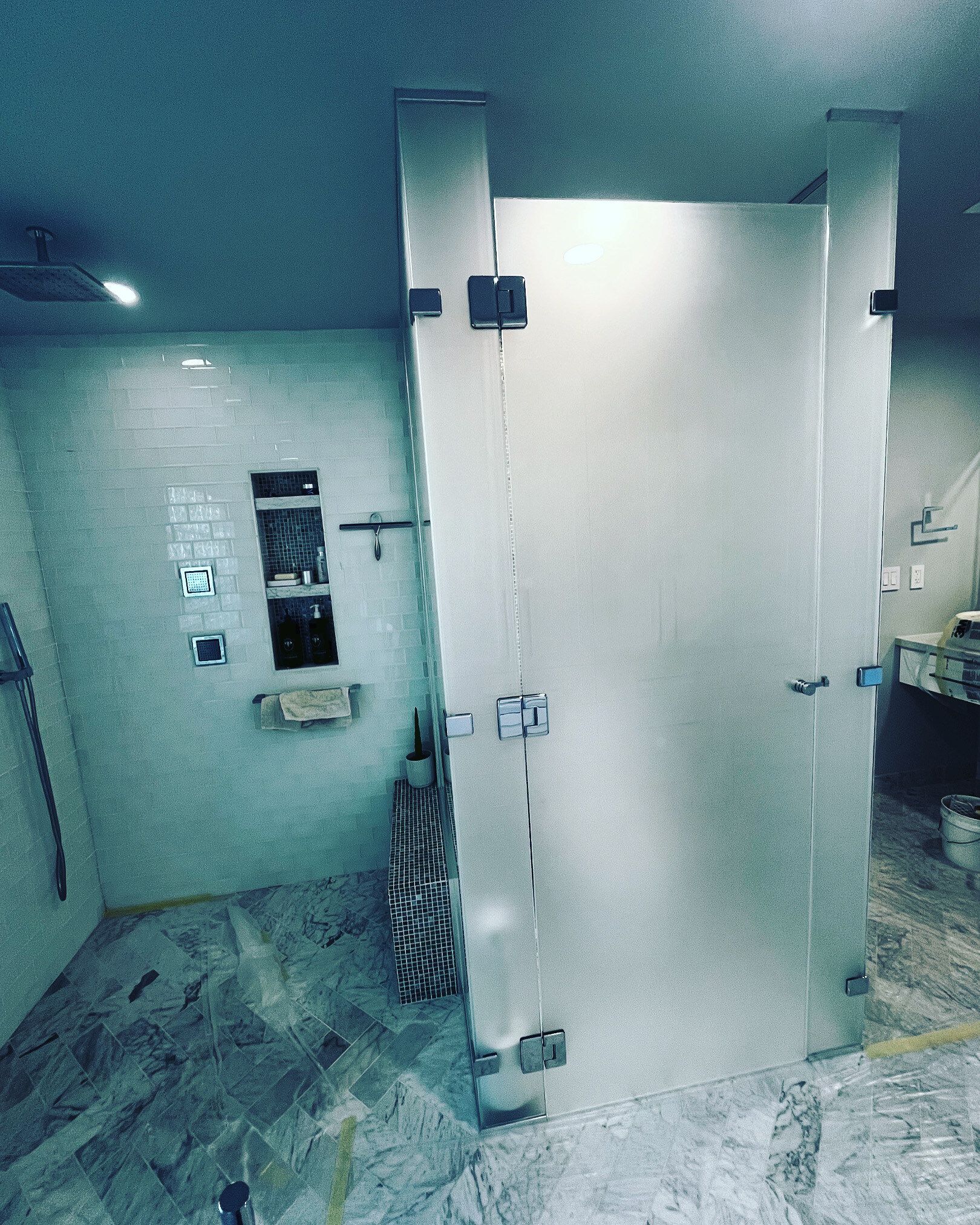 Small bathroom with an open stall door, white walls, and gray patterned floor tiles.