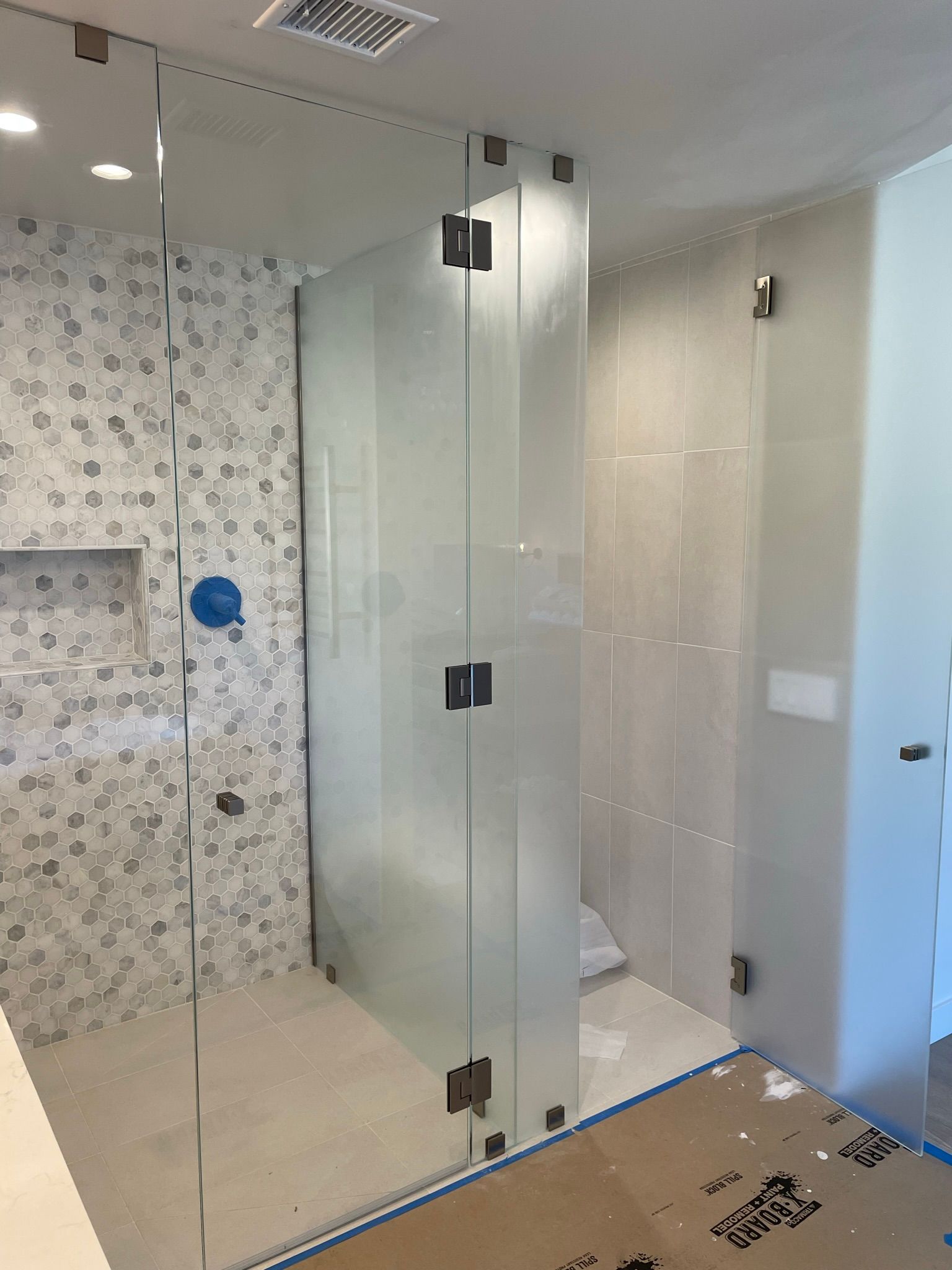 Modern bathroom with glass shower enclosure, mosaic tile wall, and white walls