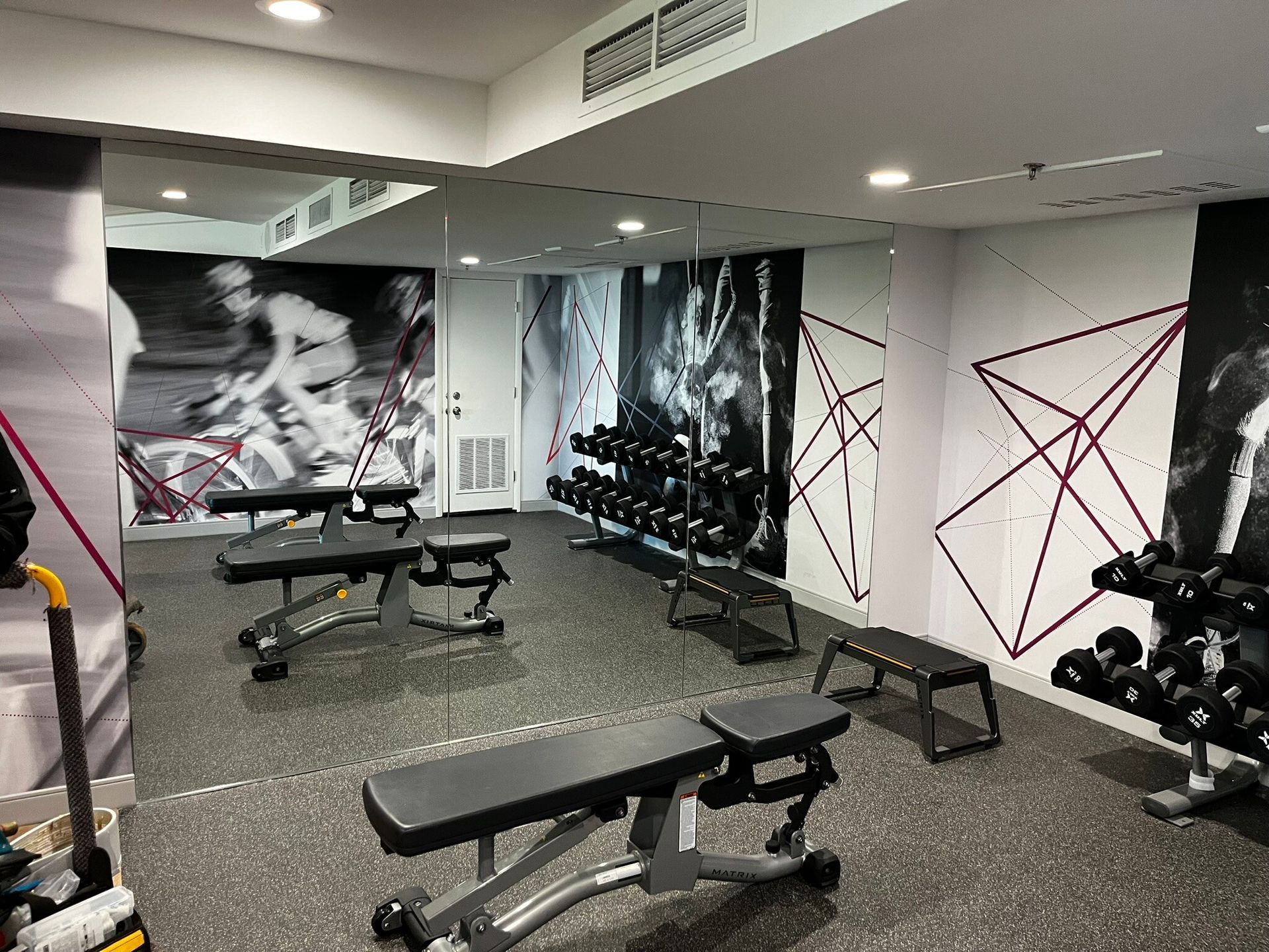 Modern gym interior with benches, dumbbells, mirrors, and black-and-white wall art.