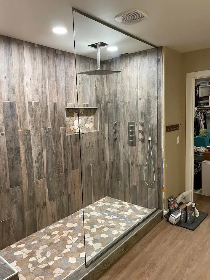 A bathroom with a walk in shower and a tub.