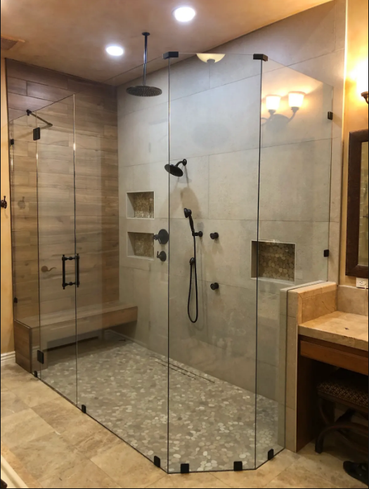 Glass walk-in shower with beige tile, built-in niche, and separate tub area in a bathroom