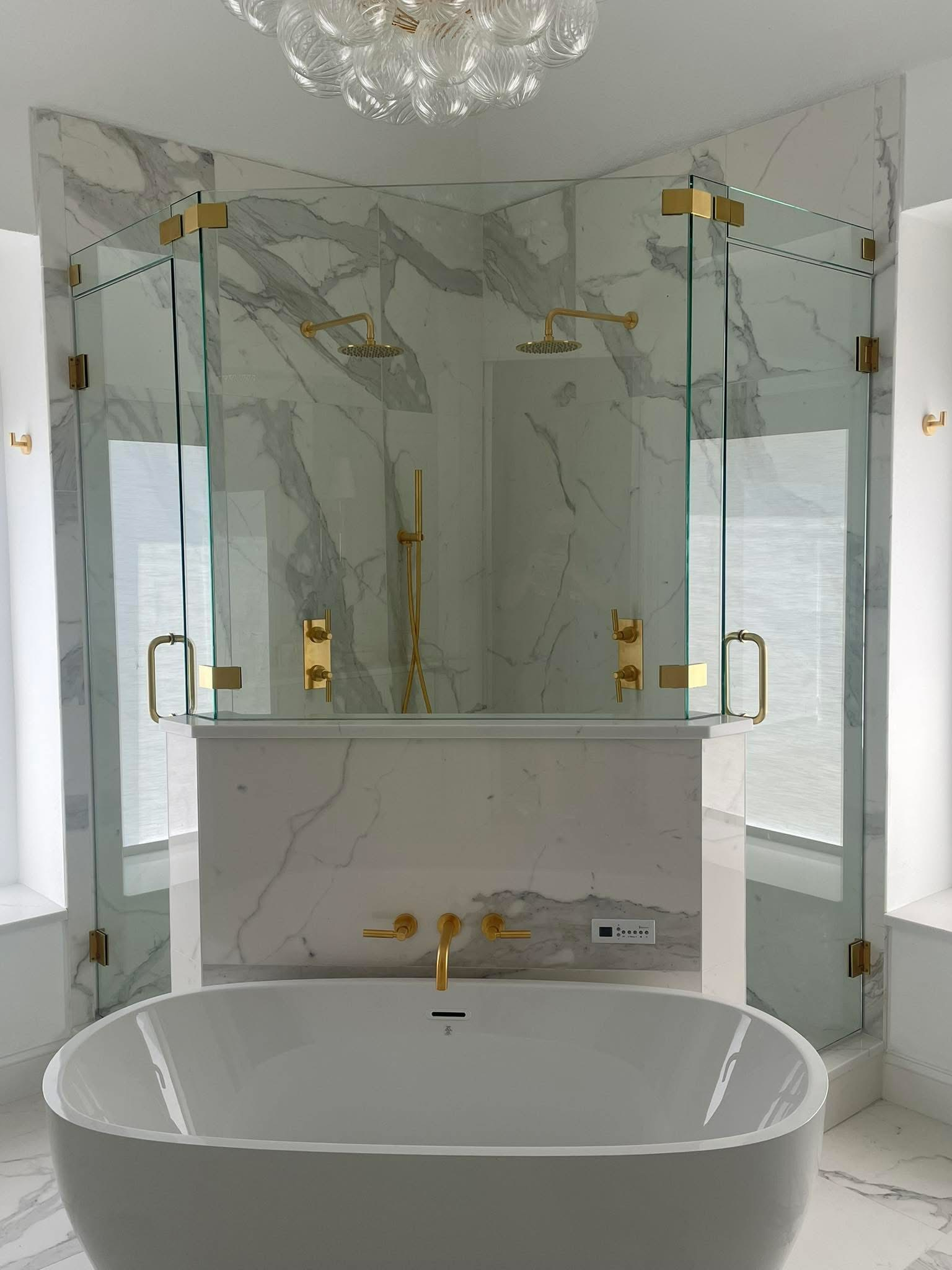 Luxurious marble bathroom with freestanding tub, glass shower, and gold fixtures