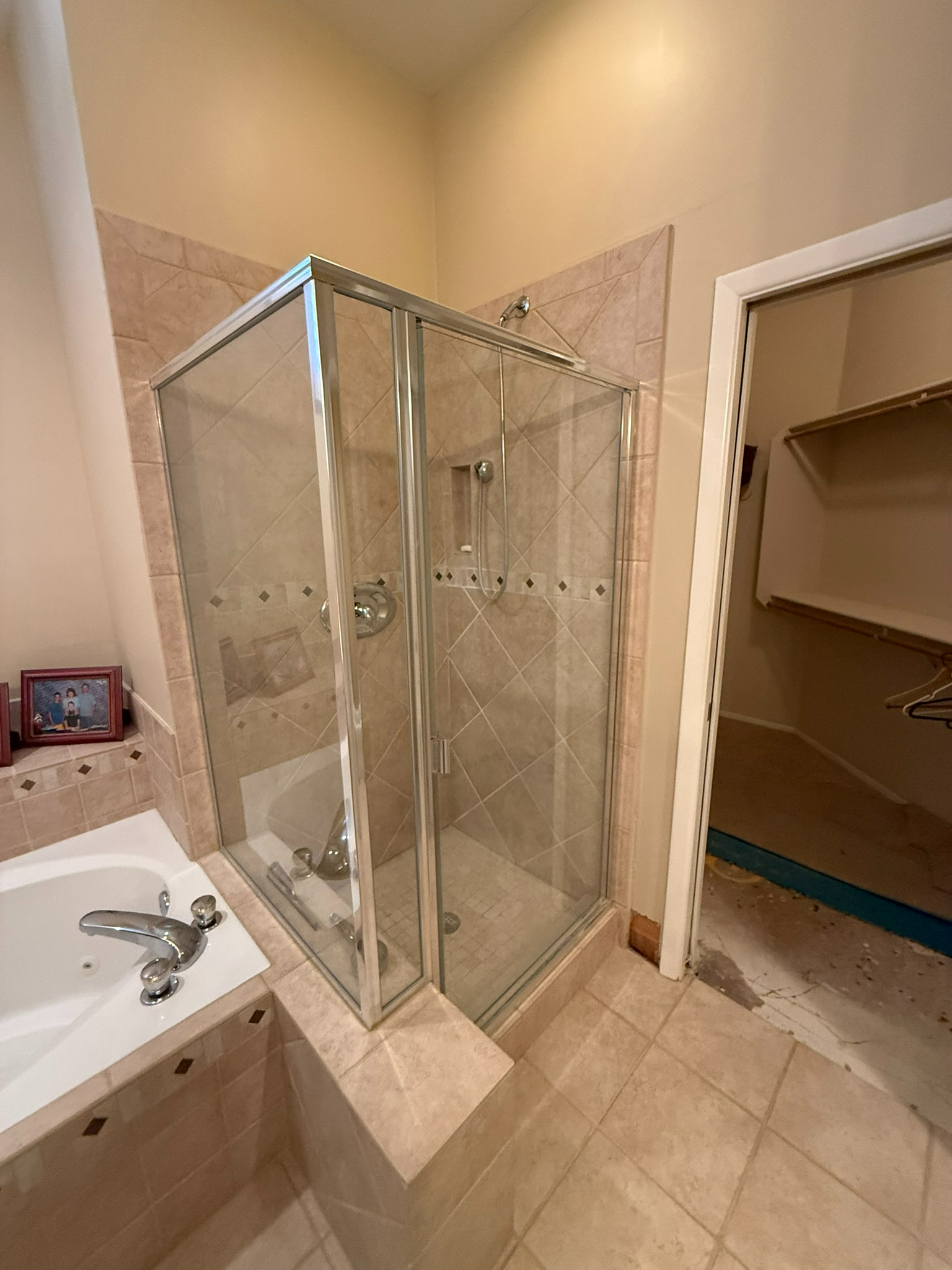 Bathroom with glass shower enclosure, sink, and open shelving on a tiled floor.