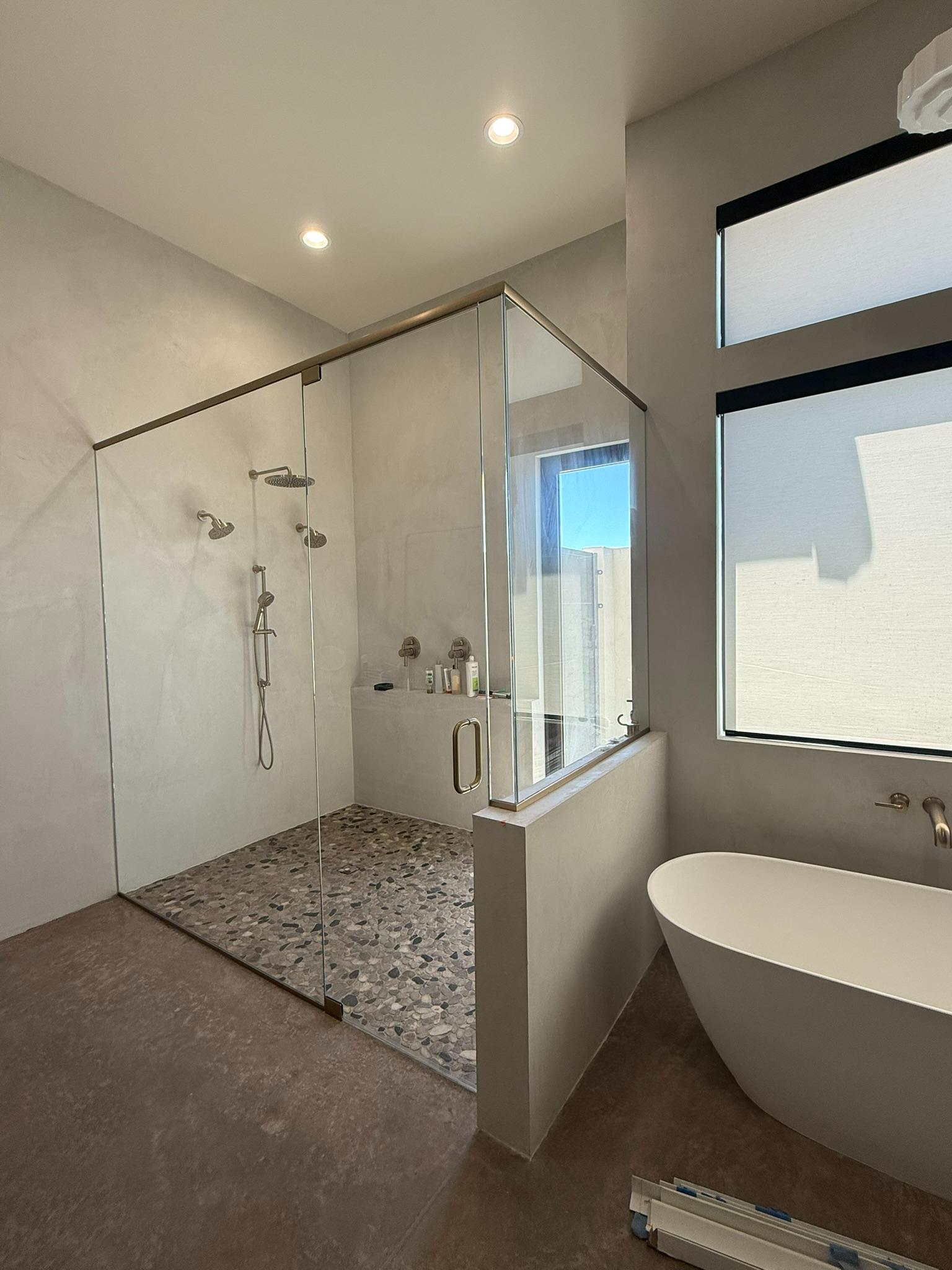 Modern bathroom with walk-in glass shower, freestanding tub, and pebble shower floor.