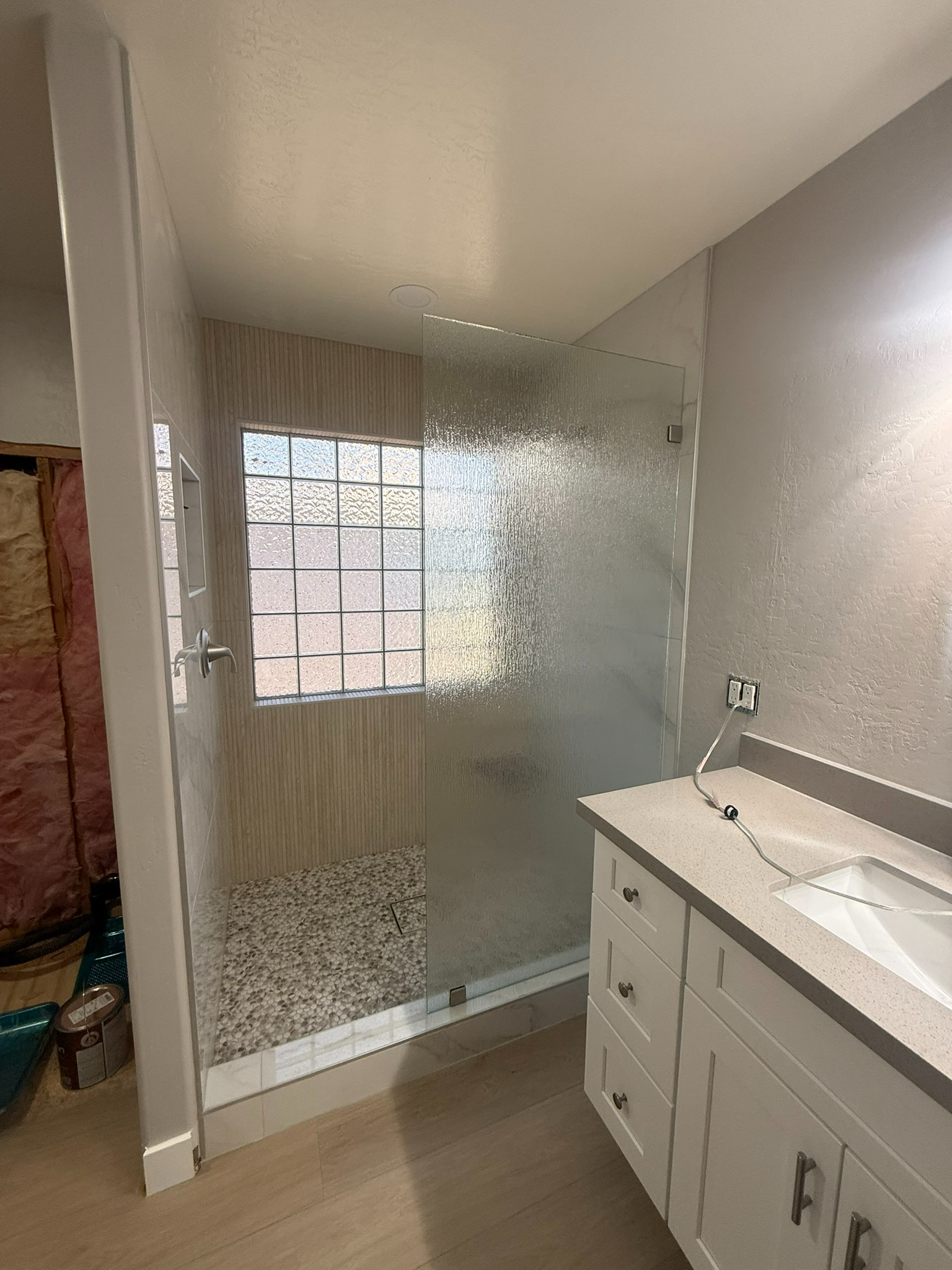 Modern bathroom with glass shower, white vanity, and window light