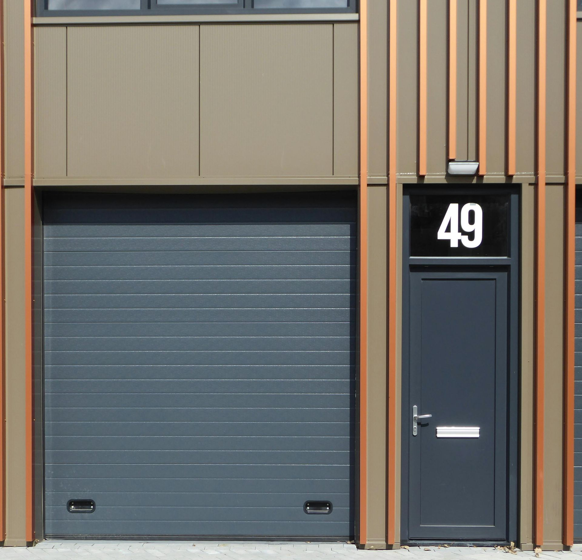 Building facade with grey garage door, dark blue door with