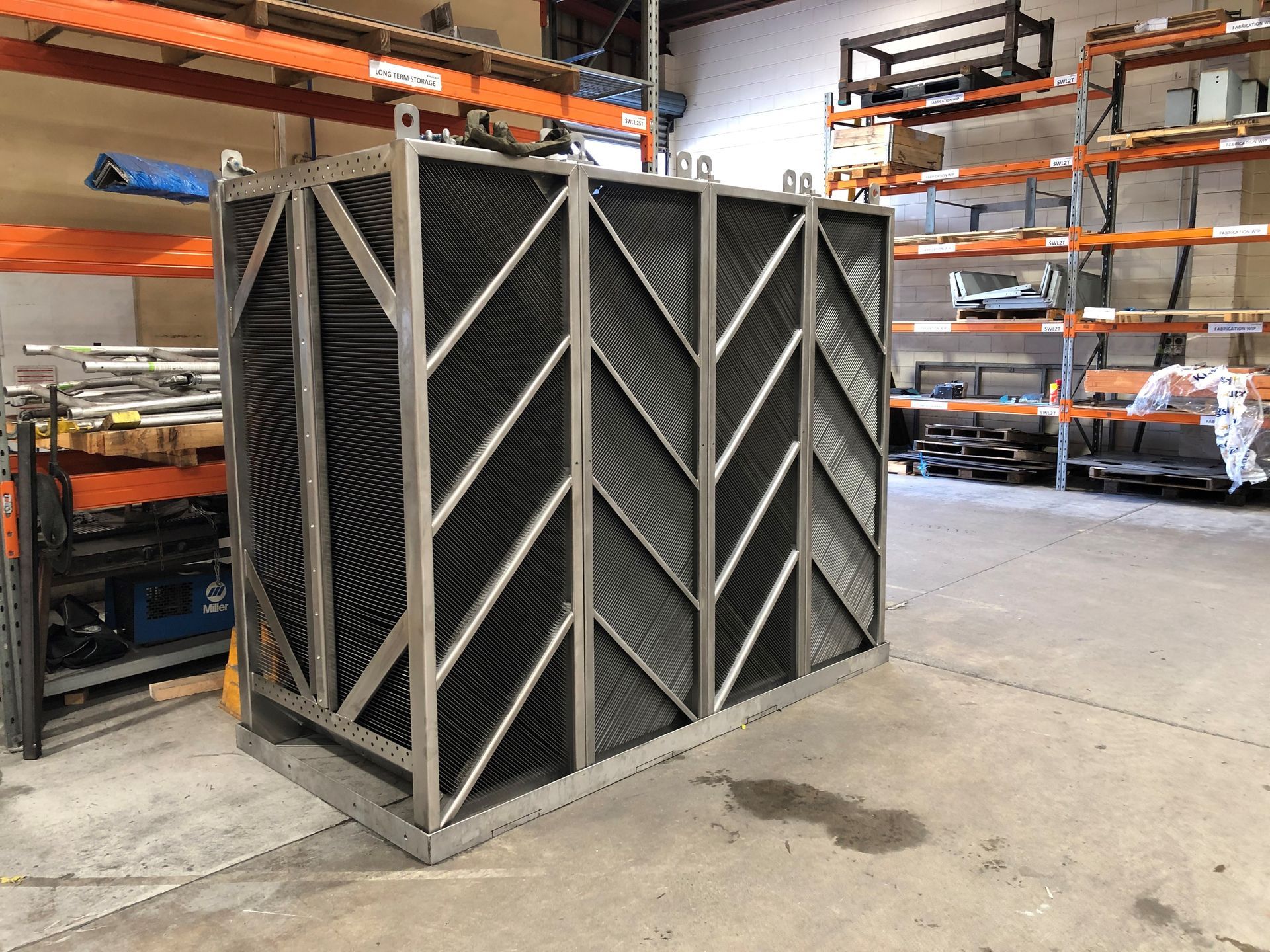 Large rectangular metal structure with angled, black internal components, in a warehouse setting.