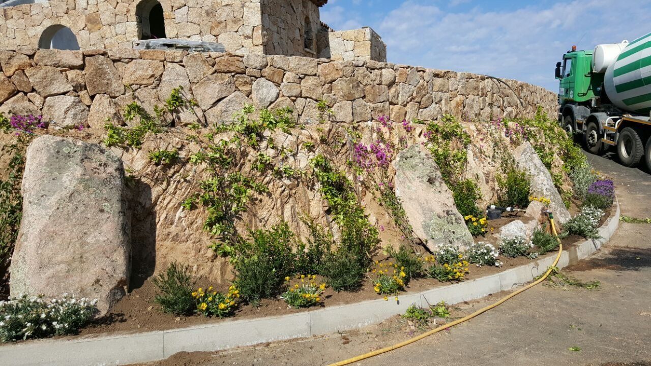 Ein Zementlaster fährt eine Straße entlang neben einer Steinmauer.
