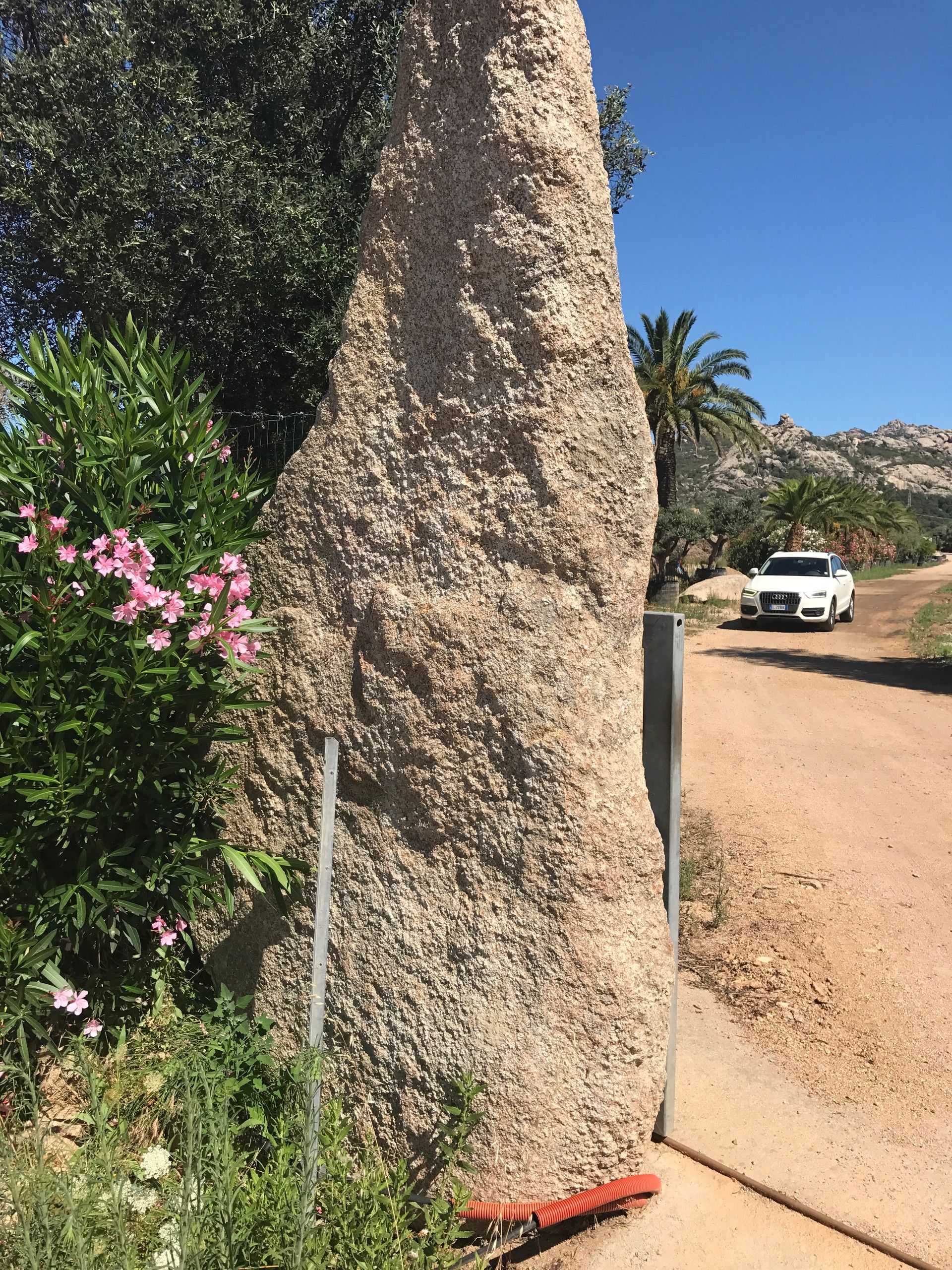 Ein Auto ist am Rand einer unbefestigten Straße neben einem großen Felsen geparkt.