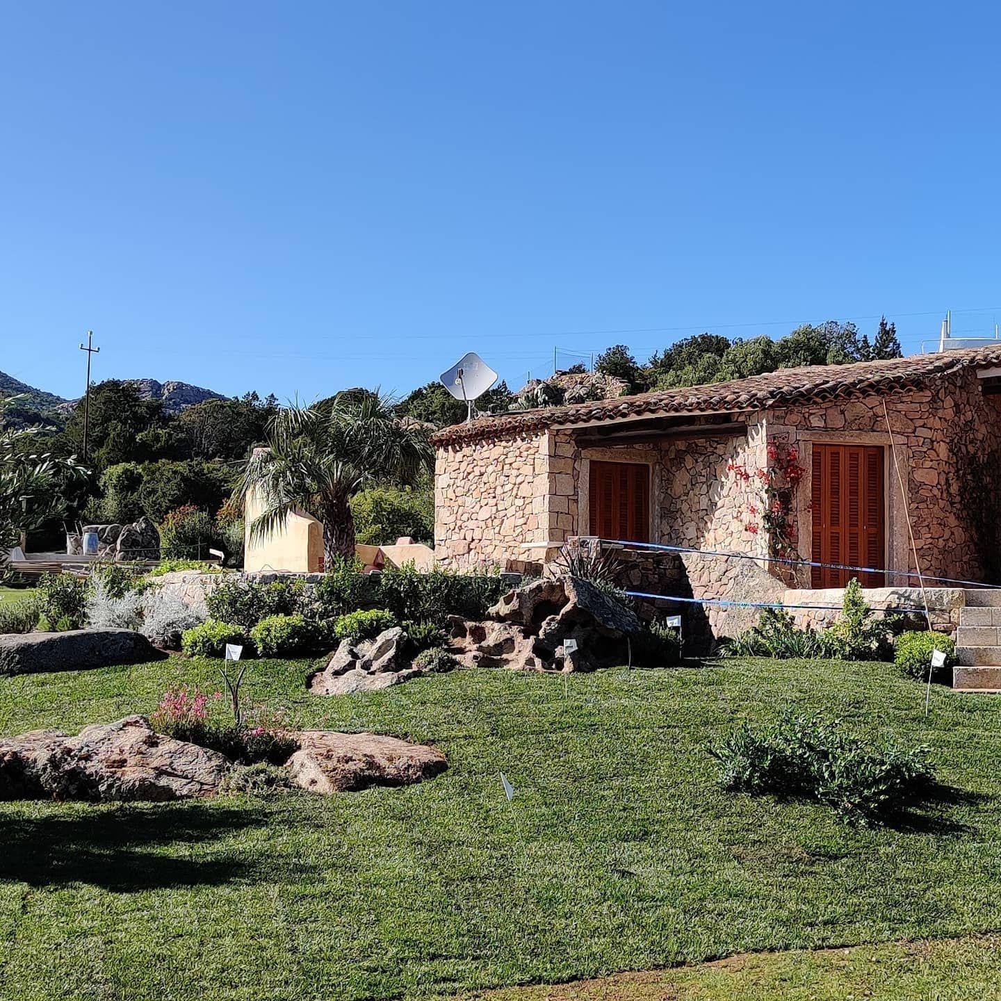 Una grande casa in pietra con un rigoglioso prato verde davanti.