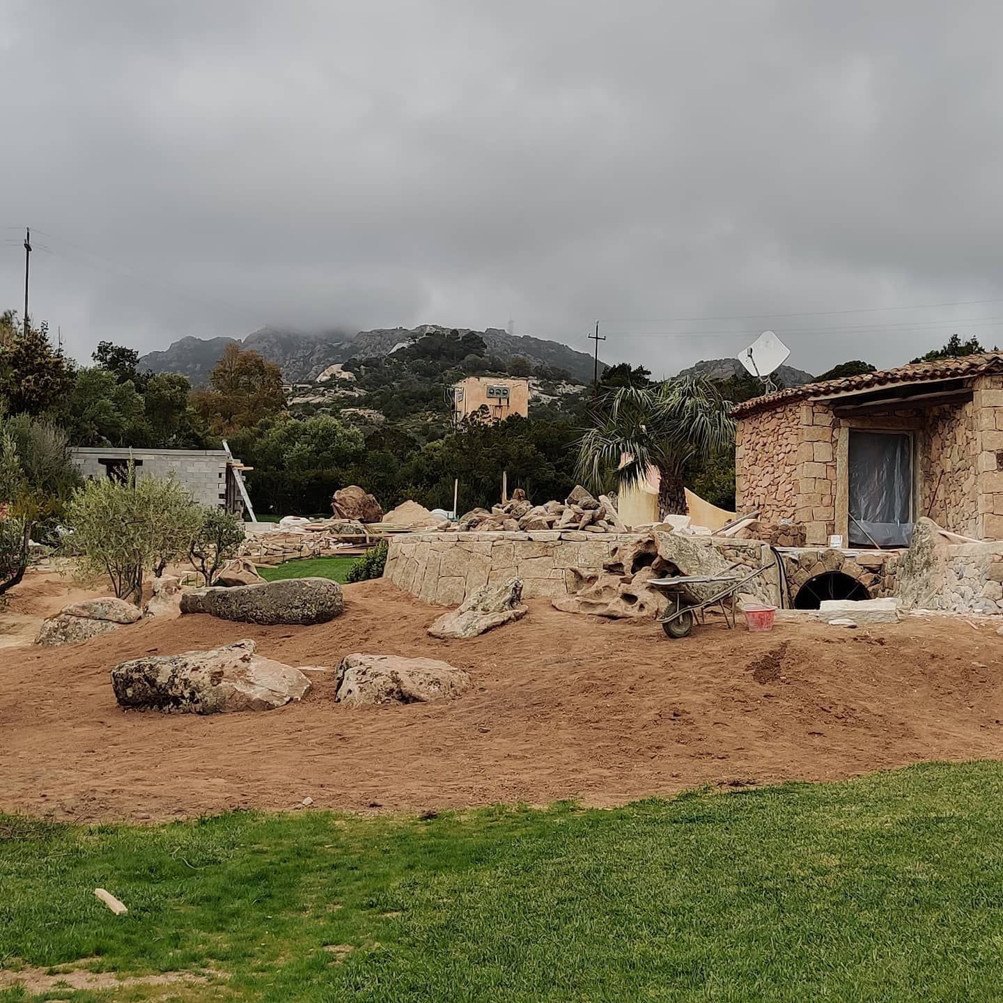 Una casa è situata nel mezzo di un campo sterrato con le montagne sullo sfondo.
