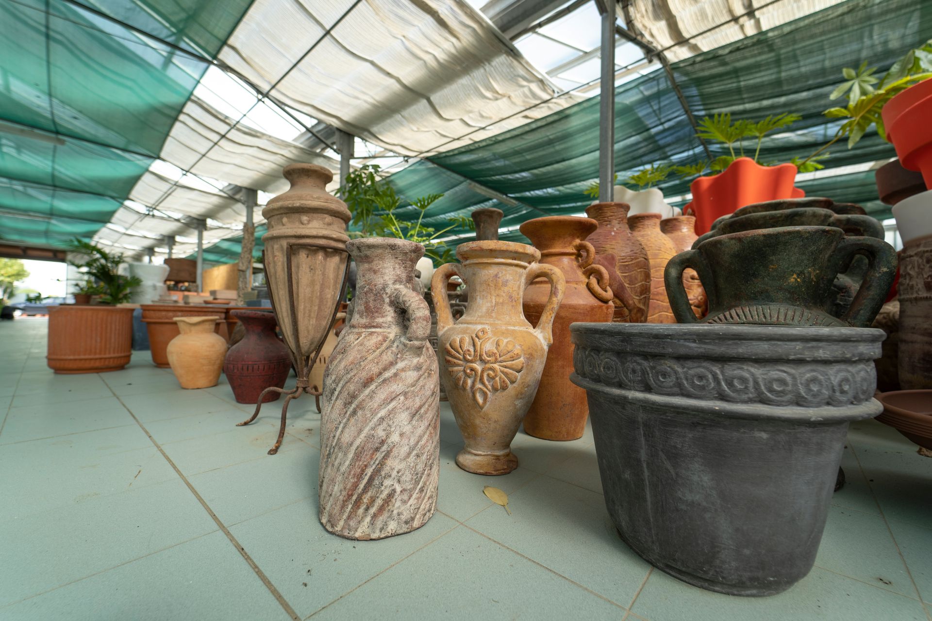 A row of pots and vases are lined up in a greenhouse.