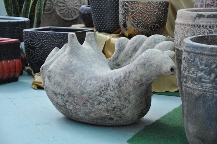On a table along with other vases sits a statue of a bird