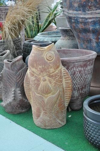 A statue of a fish is surrounded by pots and plants.