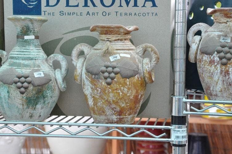 Three vases on a shelf in front of a sign that says terracotta