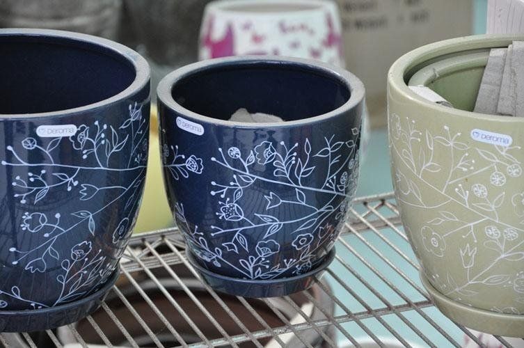Three differently coloured pots are placed on a shelf.