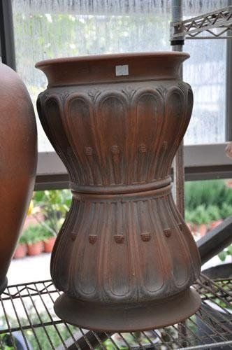 A large brown vase sits on a metal shelf.