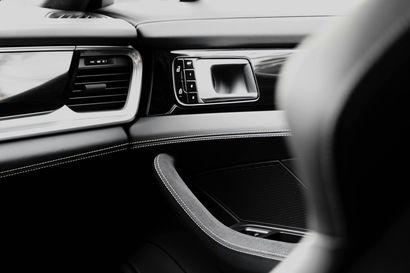 Black and white view of a car dashboard with air vents, center display, and passenger seat edge