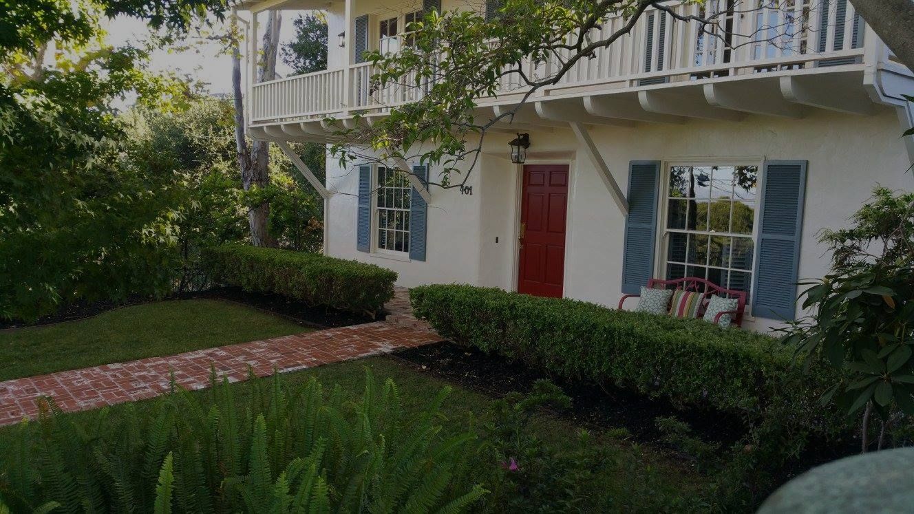 A white house with a red door and blue shutters