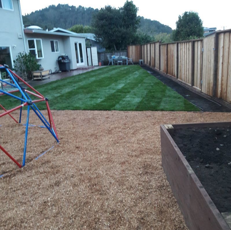 A backyard with a wooden fence and a playground