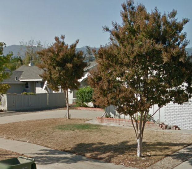 A couple of trees in front of a house with mountains in the background