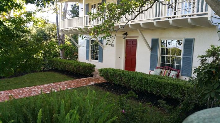 A white house with a red door and blue shutters