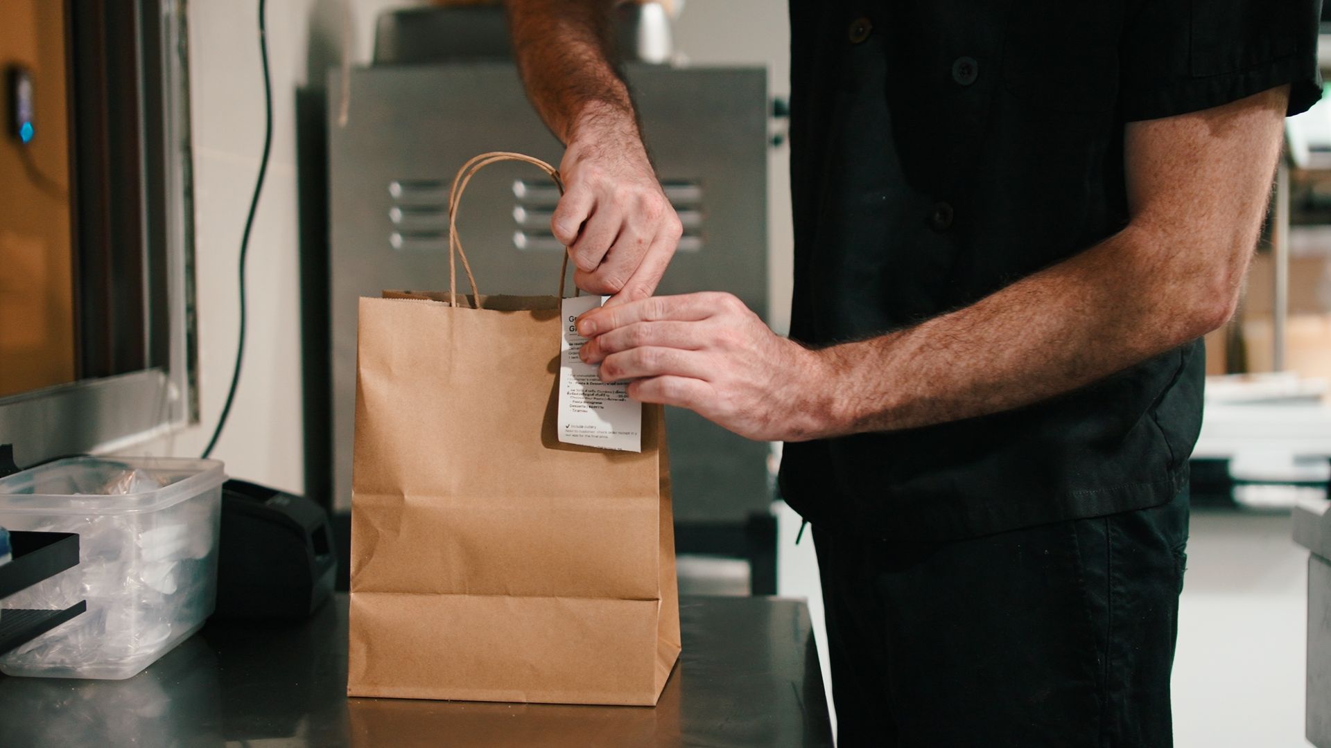 Person sealing a brown paper bag with a sticker on a kitchen counter Person sealing a brown paper bag with a sticker on a kitchen counter