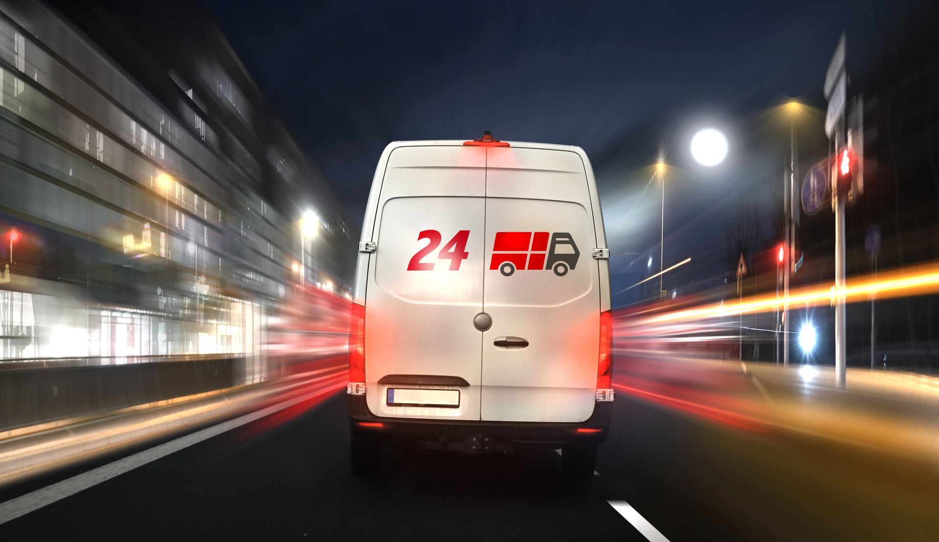 White 24/7 ambulance driving fast through a city street at night with motion blur