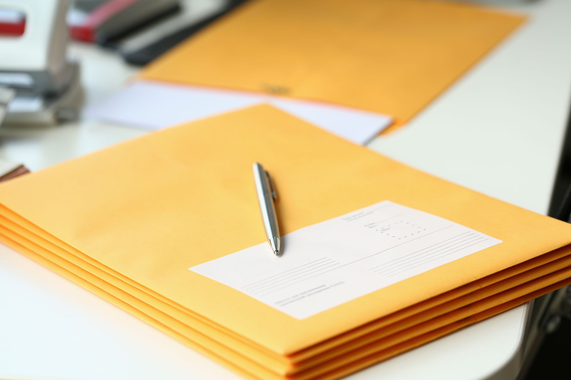 Stack of yellow envelopes with a pen on top on a desk
