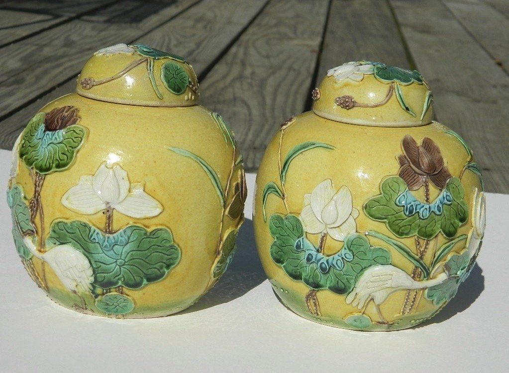 Two yellow floral ceramic jars with matching lids on a wooden surface